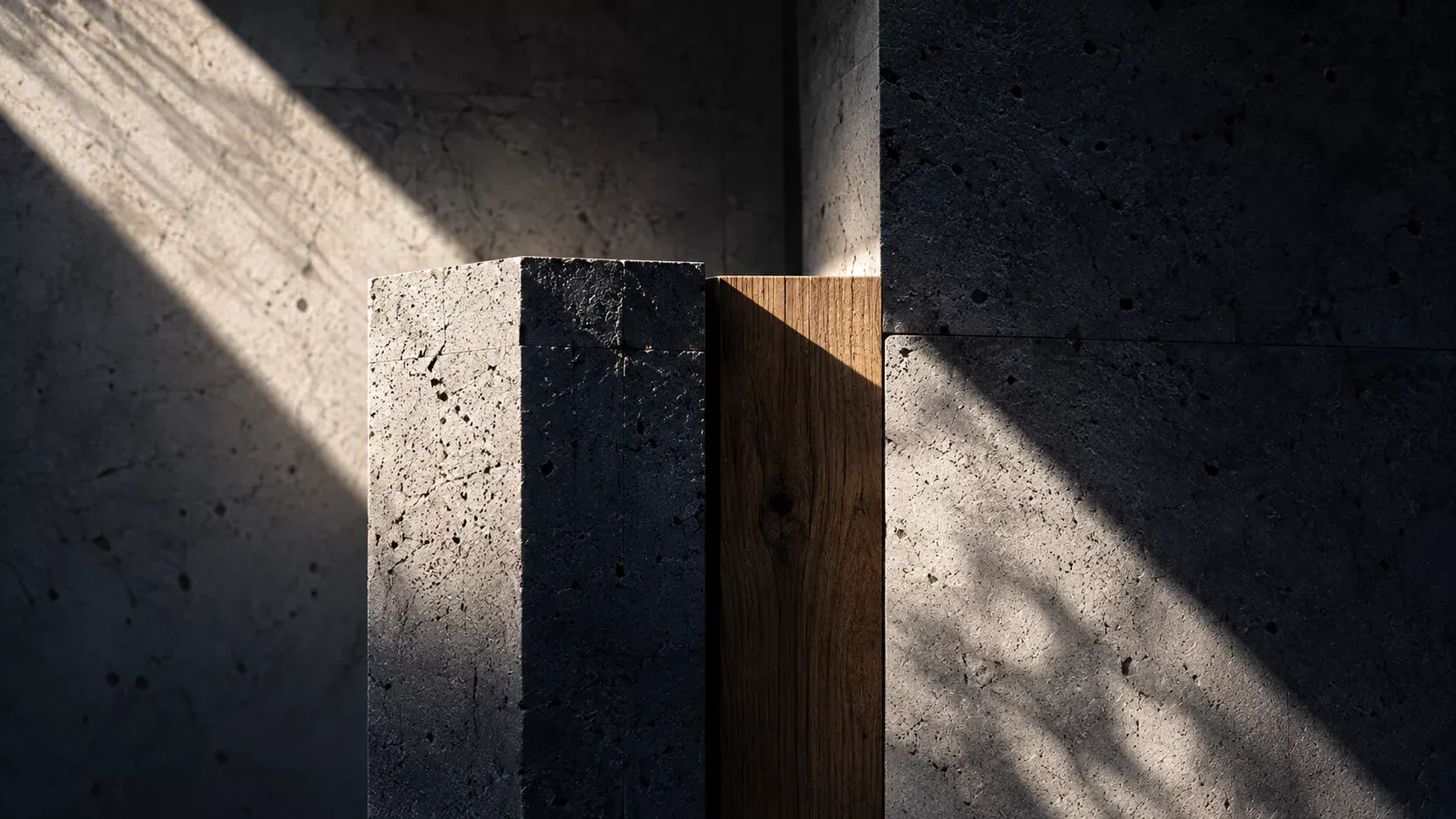 Blocs de béton et de bois assemblés, éclairés par une lumière rasante.